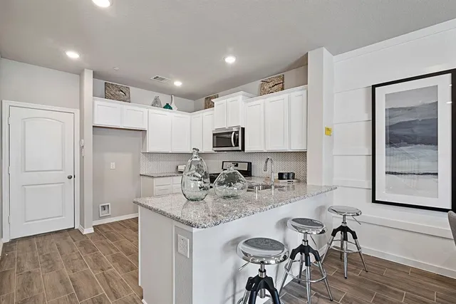 a kitchen with kitchen island granite countertop a sink cabinets and wooden floor
