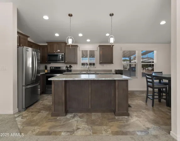 a kitchen with stainless steel appliances kitchen island granite countertop a refrigerator a stove a sink a oven and a sink