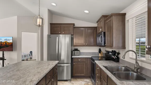a kitchen with granite countertop a sink refrigerator and cabinets