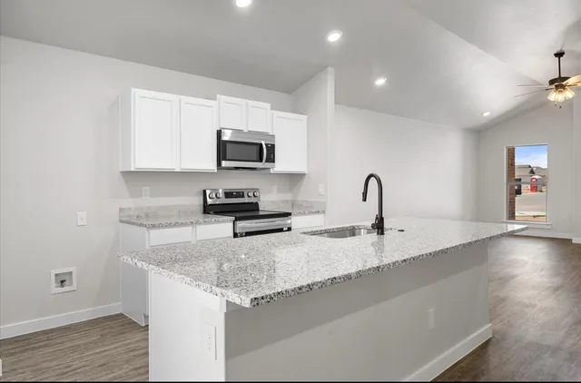 a kitchen with granite countertop a sink and a stove top oven
