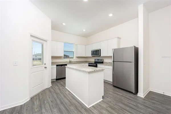 a kitchen with a refrigerator a sink dishwasher and a stove with wooden floor