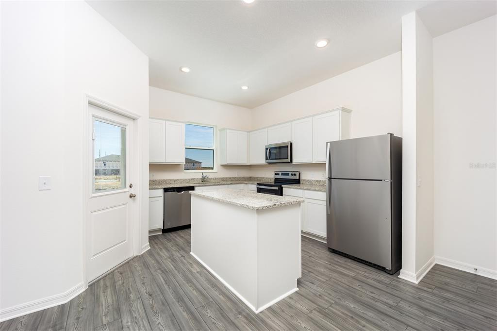 745 Poppy Lane Dundee, FL 33838 - Photo 3 of 16 a kitchen with a refrigerator a sink dishwasher and a stove with wooden floor