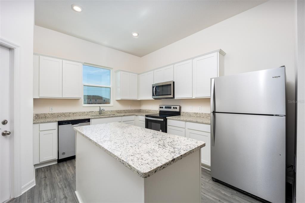 745 Poppy Lane Dundee, FL 33838 - Photo 4 of 16 a kitchen with a refrigerator a microwave a sink and cabinets