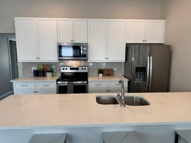 a kitchen with stainless steel appliances a refrigerator sink stove and microwave