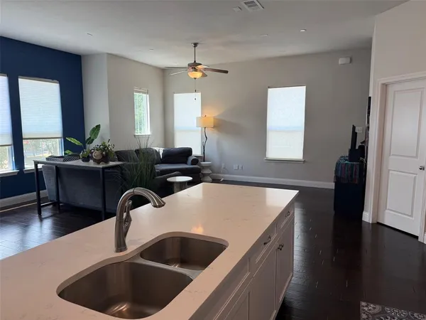 a kitchen with a sink dishwasher a refrigerator a dining table and chairs with wooden floor