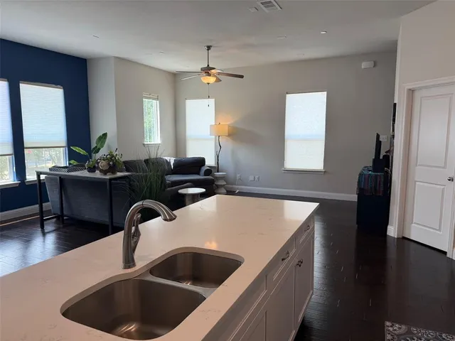 a kitchen with a sink dishwasher a refrigerator a dining table and chairs with wooden floor