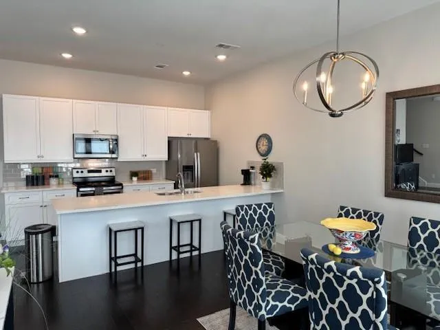 a kitchen with stainless steel appliances granite countertop a dining table chairs stove top oven and sink