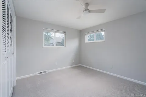 an empty room with a window and ceiling fan