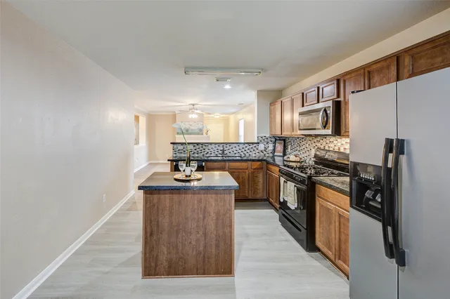 a kitchen with stainless steel appliances granite countertop a stove a sink and a refrigerator