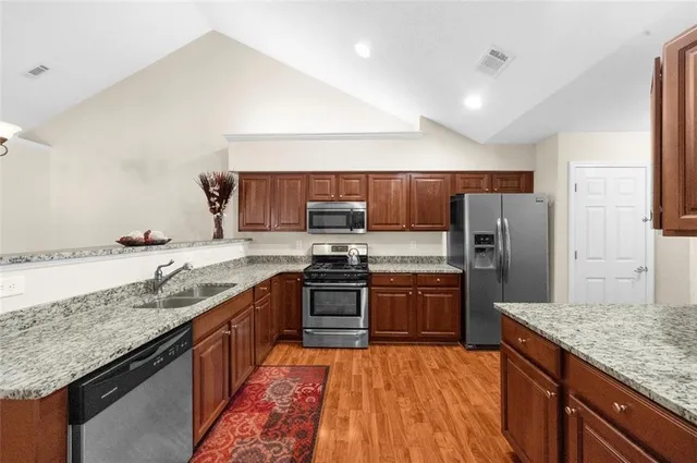 a large kitchen with granite countertop stainless steel appliances and a sink