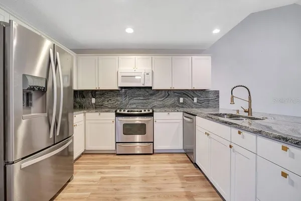 a kitchen with granite countertop white cabinets and stainless steel appliances