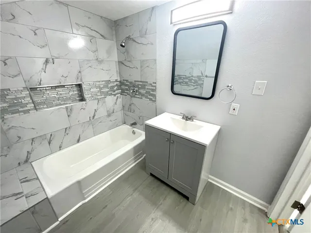 a bathroom with a tub sink and mirror