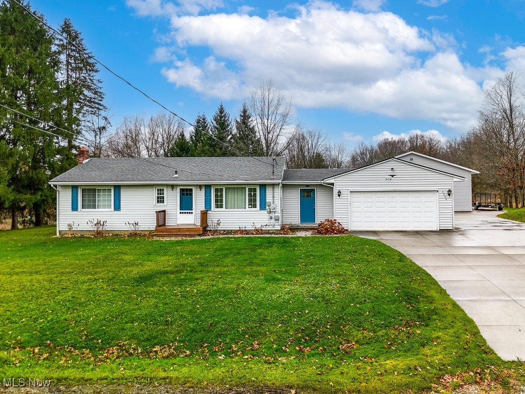 Ranch-style home featuring a garage and a front lawn