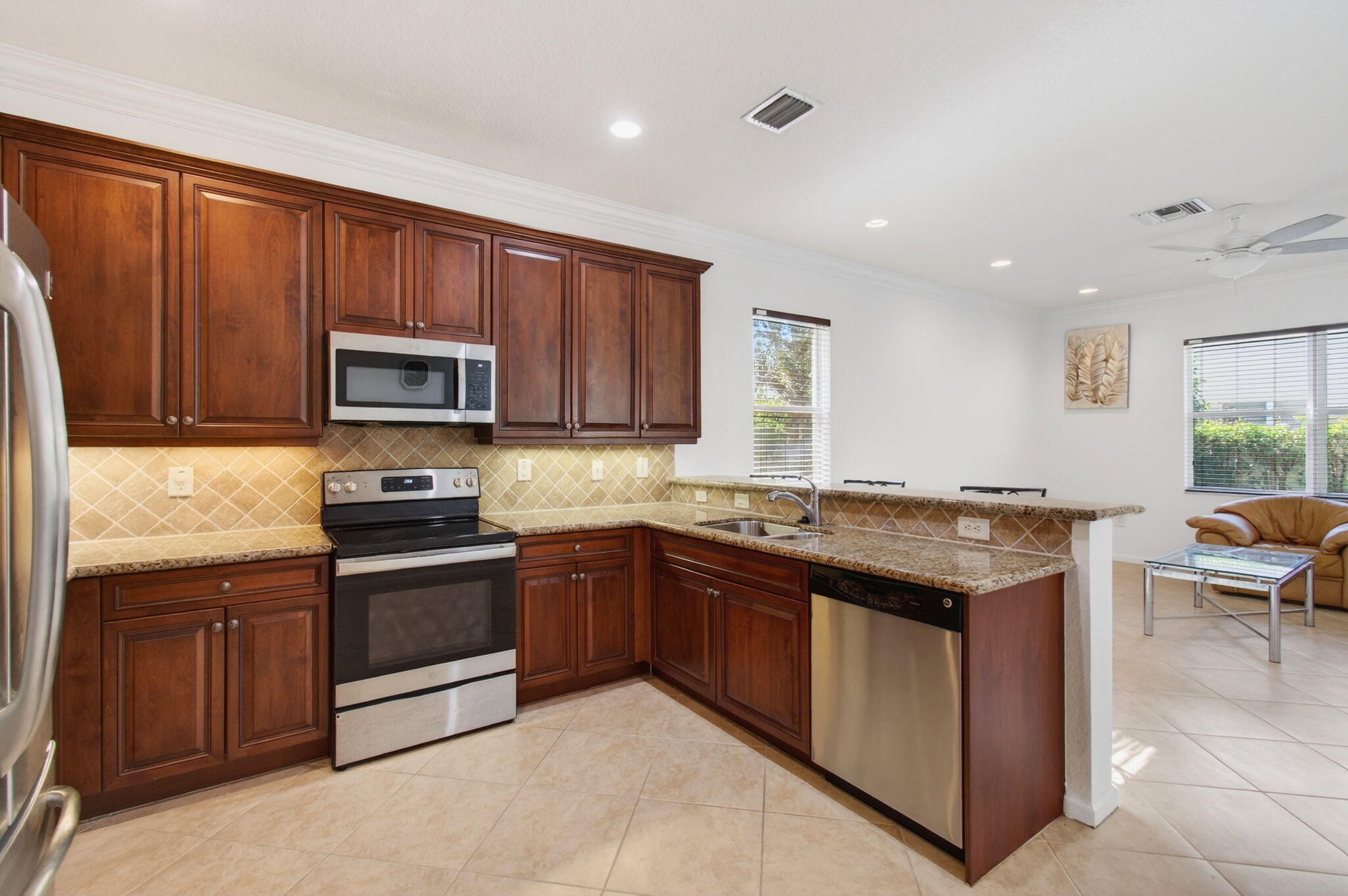 7533 Topiary Avenue Boynton Beach, FL 33437 - Photo 23 of 90 a kitchen with stainless steel appliances granite countertop wooden cabinets a stove top oven a sink and dishwasher