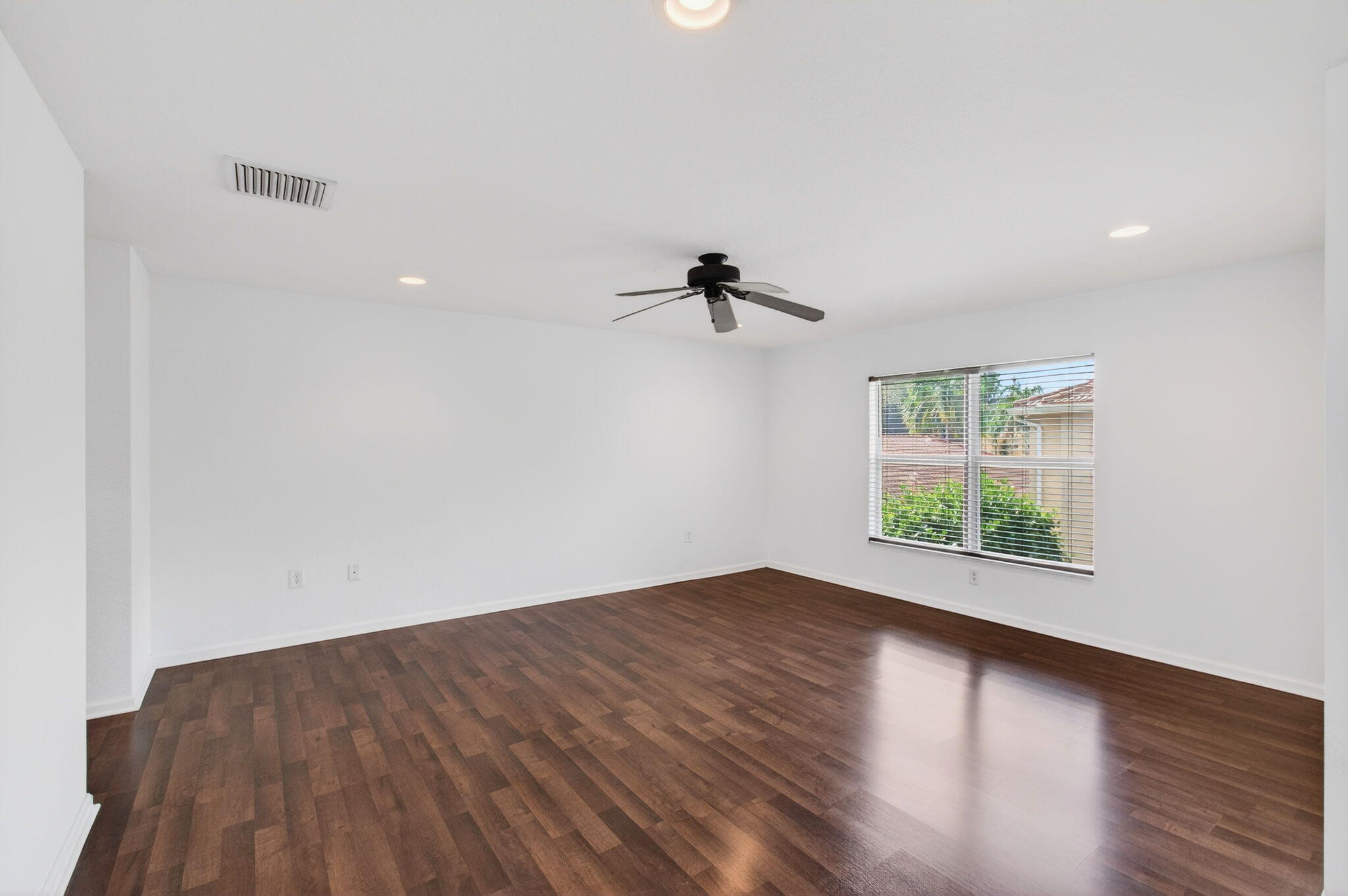 7533 Topiary Avenue Boynton Beach, FL 33437 - Photo 56 of 90 an empty room with wooden floor chandelier fan and windows