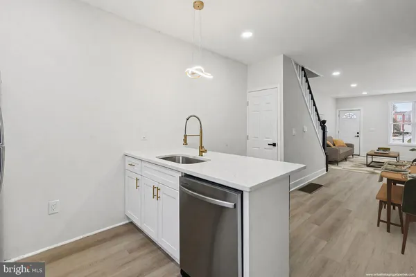 a kitchen with a sink a stove and chairs with wooden floor