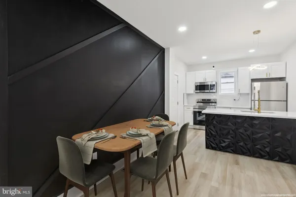 a kitchen with stainless steel appliances kitchen island granite countertop a sink a stove a refrigerator with a dining table and chairs