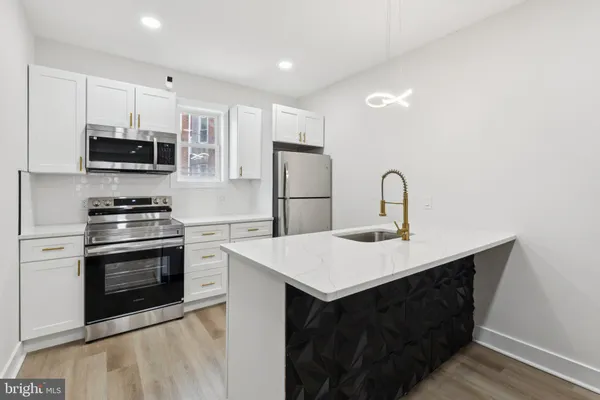 a kitchen with stainless steel appliances a sink a stove a microwave and cabinets