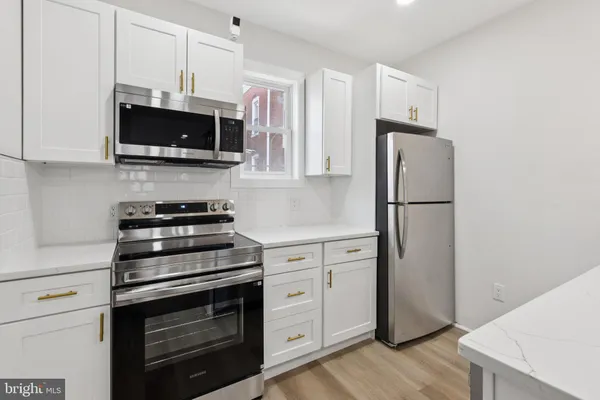 a kitchen with stainless steel appliances white cabinets and a stove a refrigerator with wooden floor