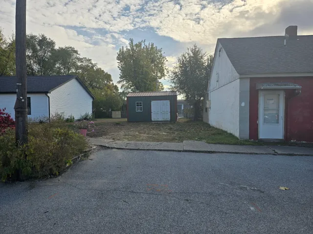 a view of a grey house with a yard and large tree