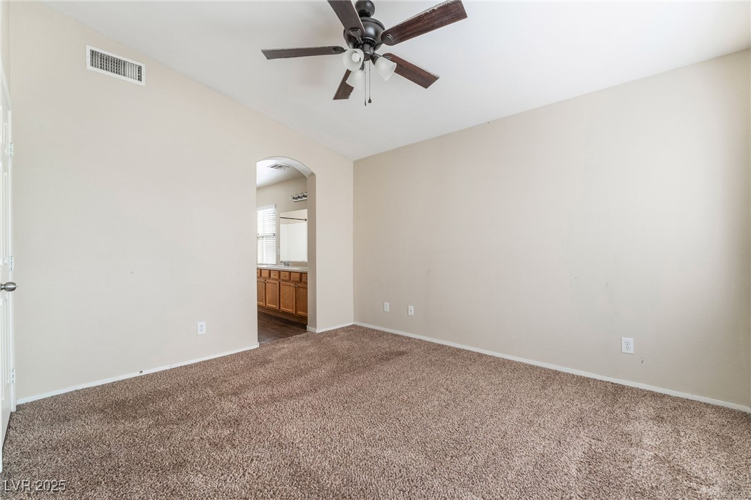 1570 Rusty Ridge Lane Henderson, NV 89002 - Photo 24 of 35 Carpeted empty room with baseboards, vaulted ceiling, visible vents, ceiling fan, and arched walkways