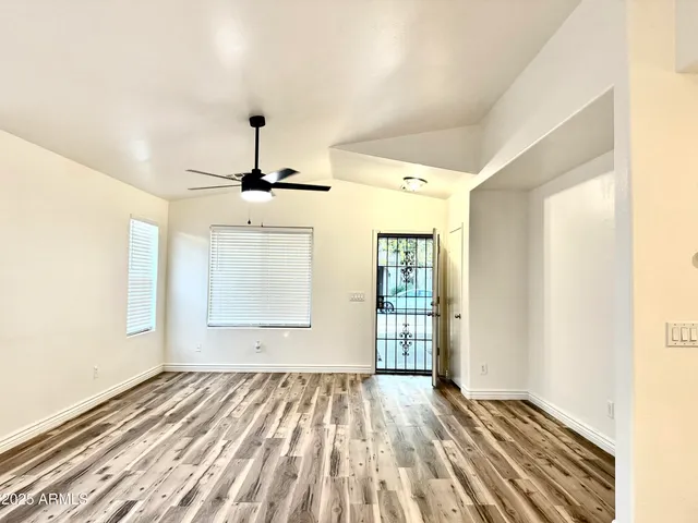 a view of empty room with wooden floor and fan