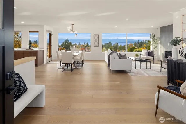 a living room with furniture floor to ceiling window and a kitchen view