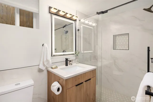 a bathroom with a sink a toilet a mirror a vanity and shower