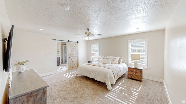 368 East 700 North Springville, UT 84663 - Photo 9 of 55 Bedroom with a barn door, a textured ceiling, light carpet, a ceiling fan, and ensuite bath