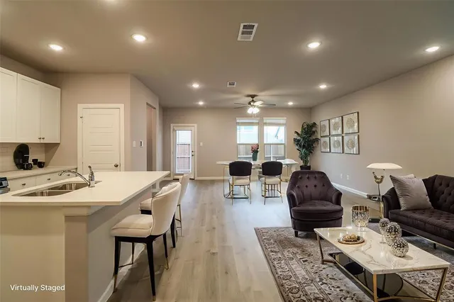 a living room with furniture a table and kitchen view