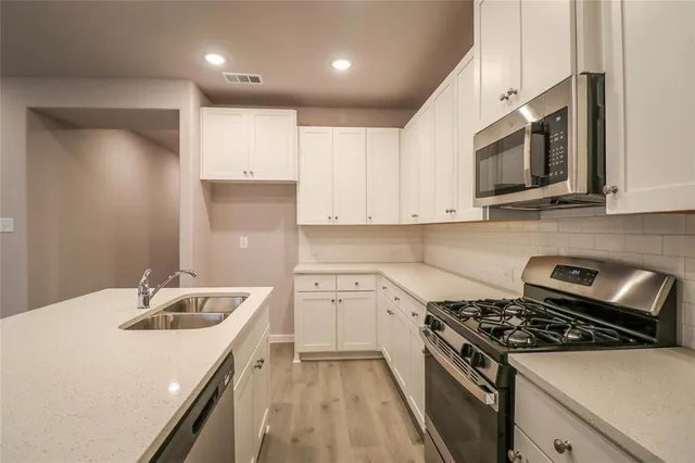 a kitchen with stainless steel appliances granite countertop a sink stove microwave and cabinets