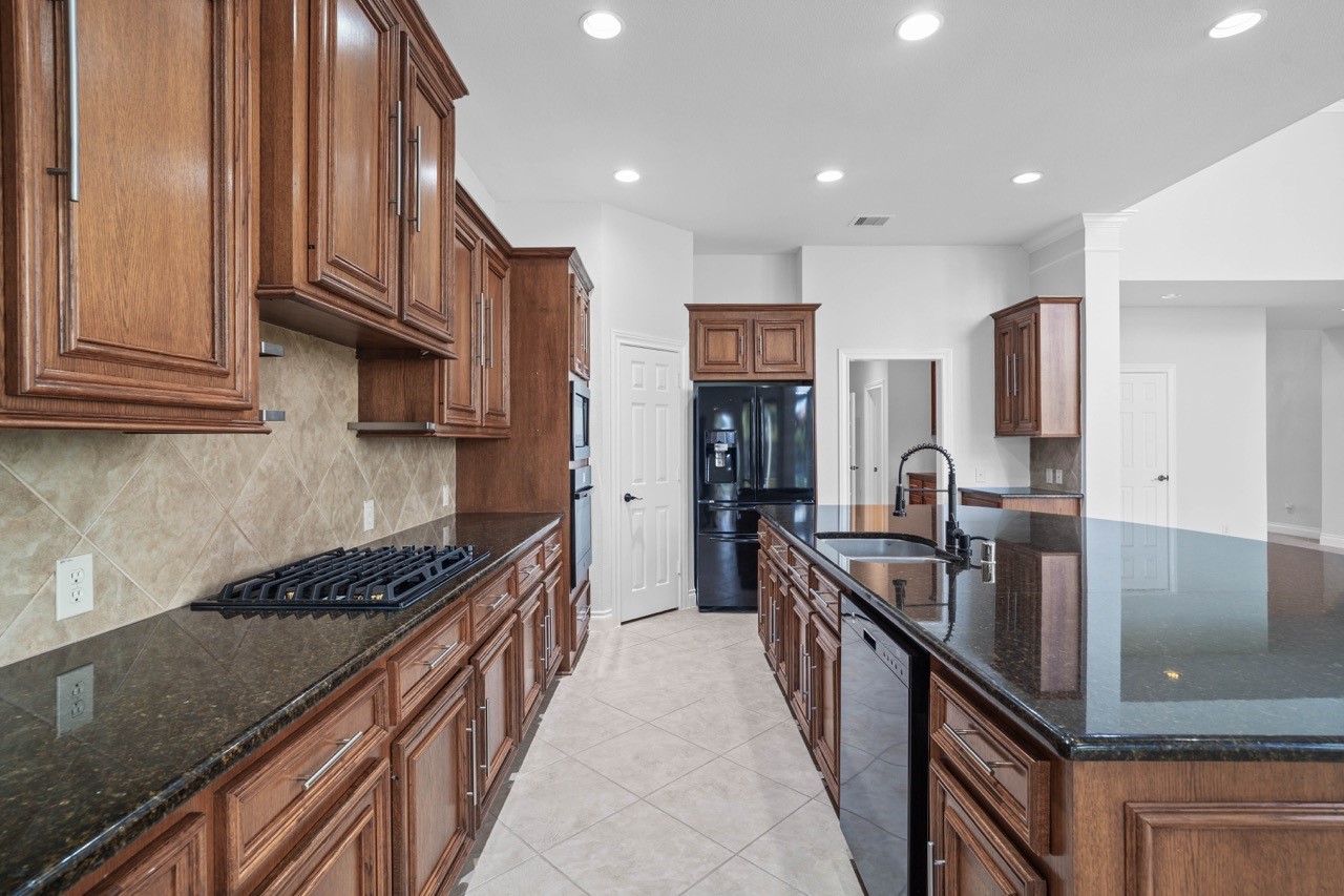 26411 Ridgefield Park Lane Cypress, TX 77433 - Photo 19 of 50 a kitchen with kitchen island granite countertop a sink and wooden cabinets