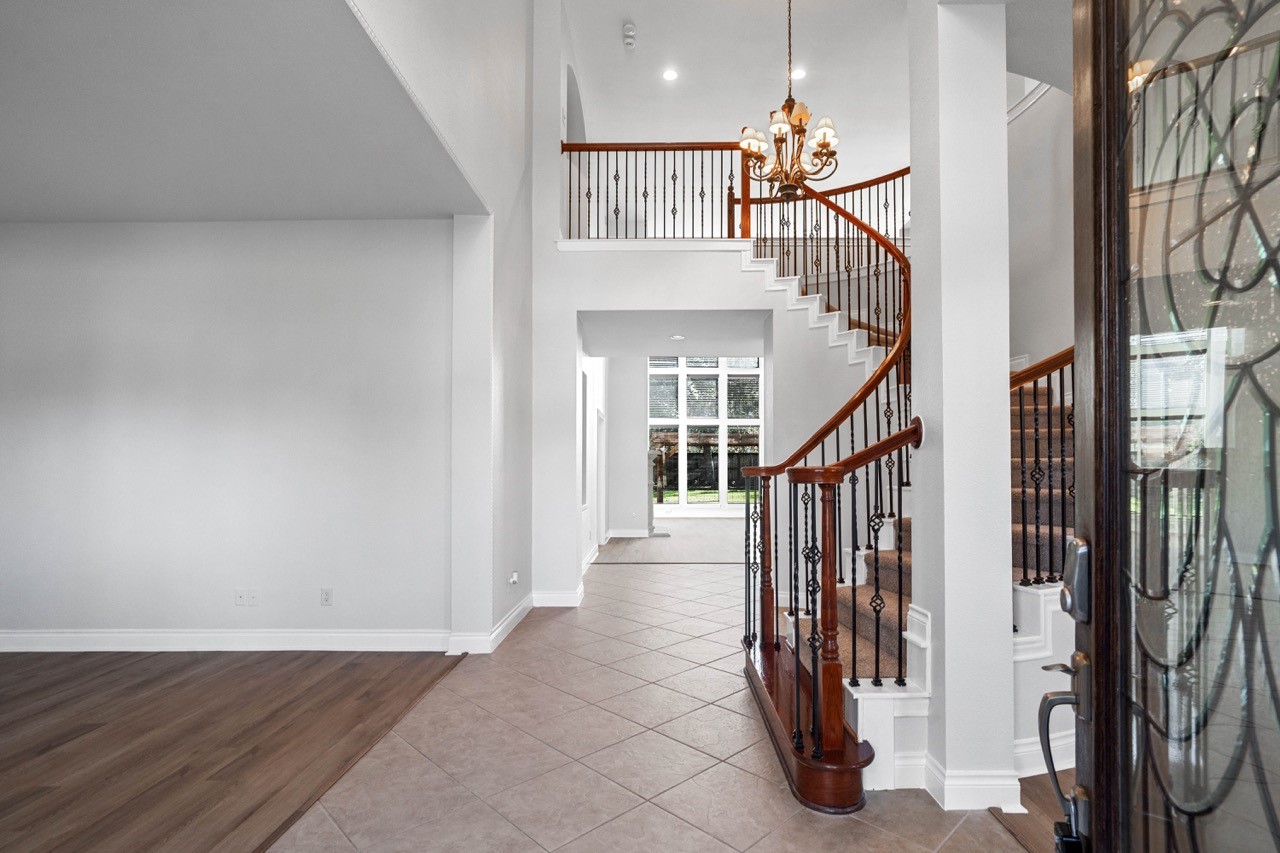 26411 Ridgefield Park Lane Cypress, TX 77433 - Photo 2 of 50 View this bright entryway with a stunning curved staircase featuring wood and iron details. The space is open with high ceilings, tile flooring, and leads to a large windowed area, creating a welcoming and elegant first impression.