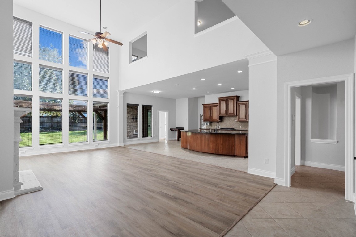 26411 Ridgefield Park Lane Cypress, TX 77433 - Photo 10 of 50 This spacious, open-concept living area features high ceilings and large windows that flood the space with natural light. The adjacent kitchen boasts modern cabinetry and a central island, perfect for entertaining. The room's design combines elegance and functionality with a seamless flow to the outdoor view.