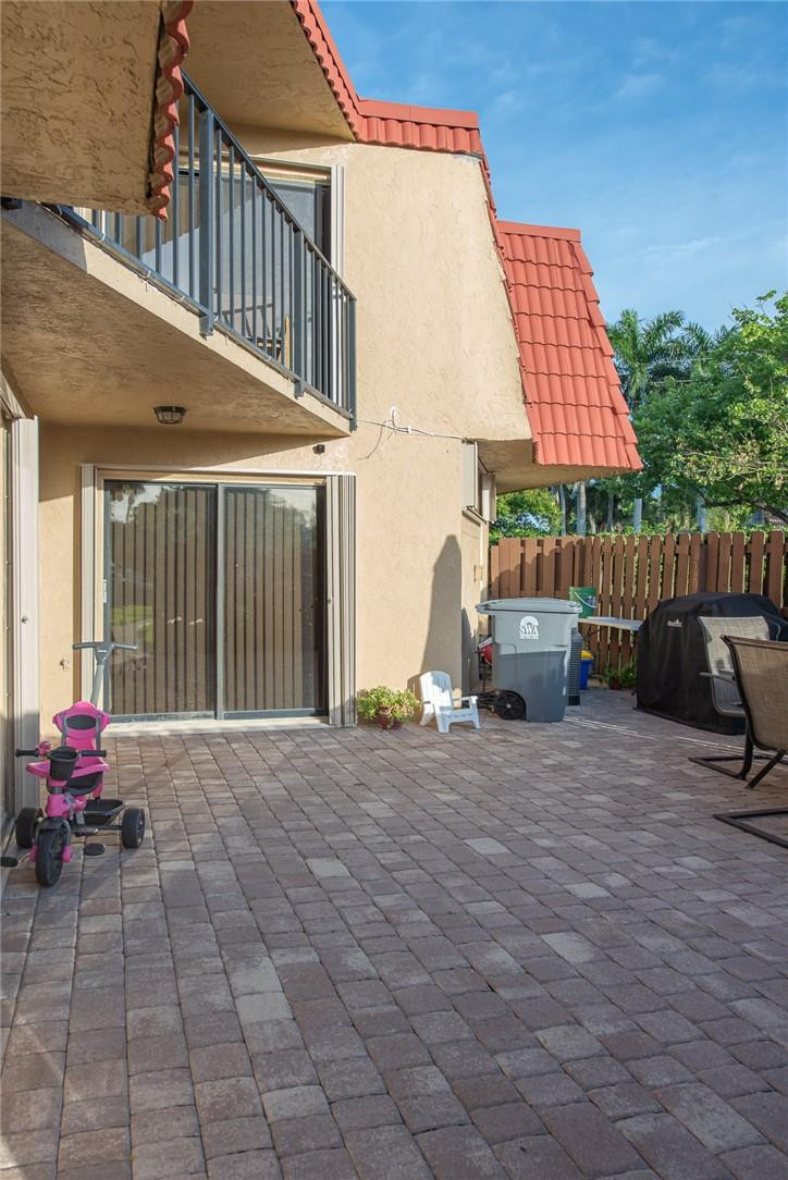 8116 Thames Boulevard, Unit A Boca Raton, FL 33433 - Photo 16 of 27 a view of a patio with a table and chairs under an umbrella
