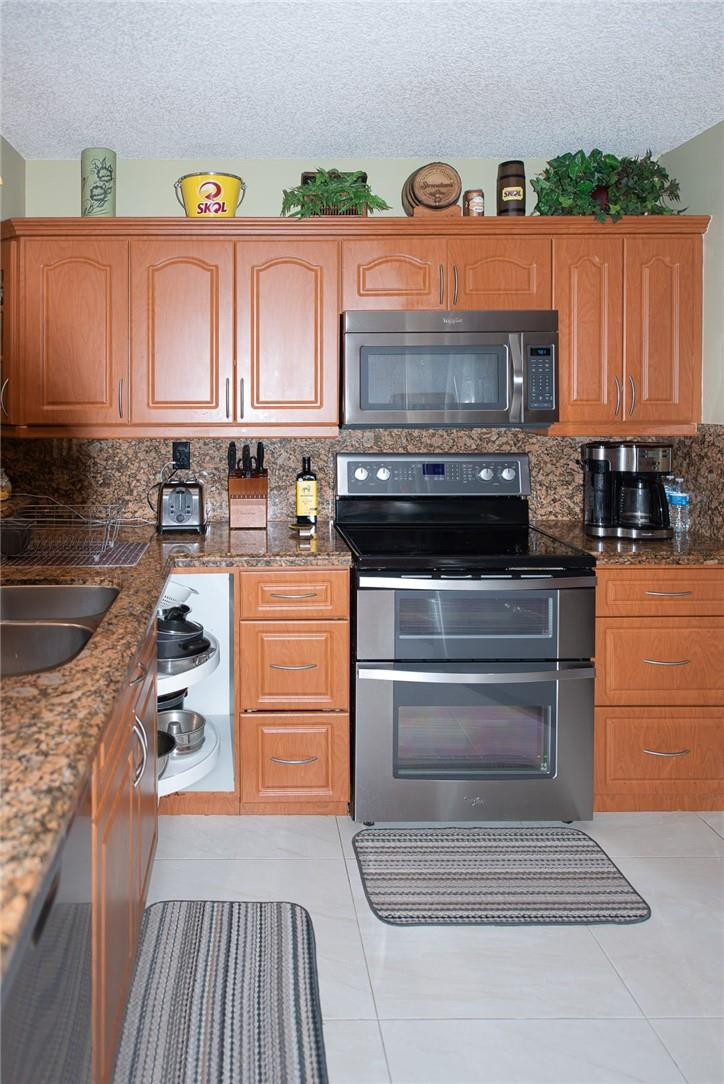 8116 Thames Boulevard, Unit A Boca Raton, FL 33433 - Photo 6 of 27 a kitchen with granite countertop a stove and a refrigerator