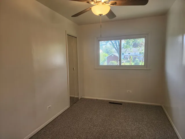 an empty room with a ceiling fan and a window