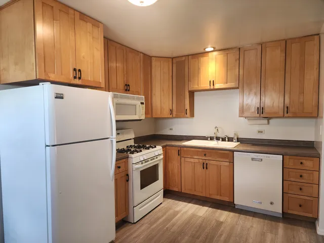 a white refrigerator freezer sitting inside of a kitchen with stainless steel appliances granite countertop wooden cabinets a washer dryer and white cabinets