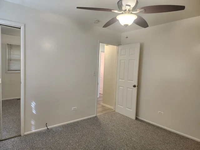 an empty room with closet and a chandelier fan
