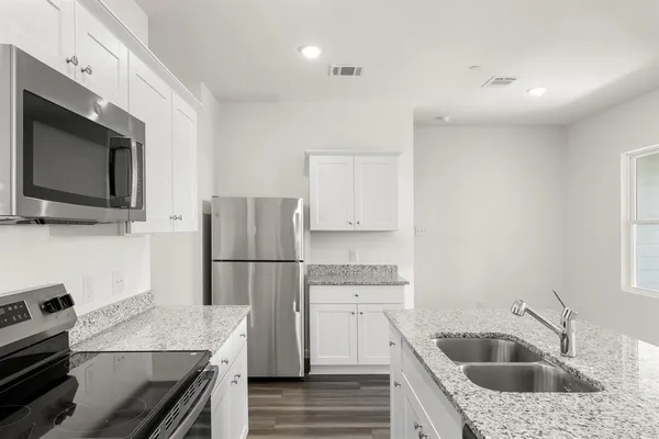 a view of a kitchen with white cabinets and wooden floor