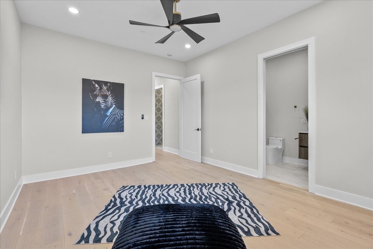 516 Reinerman Street Houston, TX 77007 - Photo 24 of 42 This spacious bedroom features light hardwood floors, a modern ceiling fan, and neutral walls. It includes an ensuite bathroom and a walk-in closet. Artwork and a stylish rug add a touch of personality.