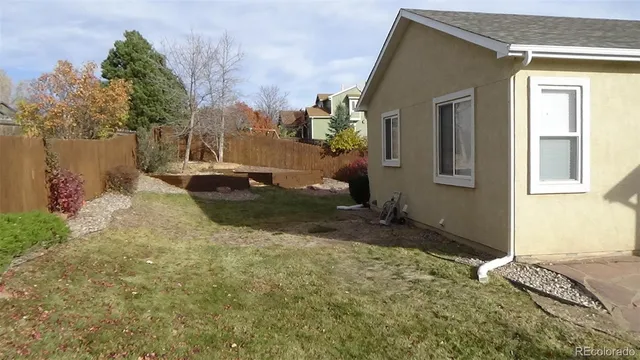 a view of backyard with potted plants and wooden fence
