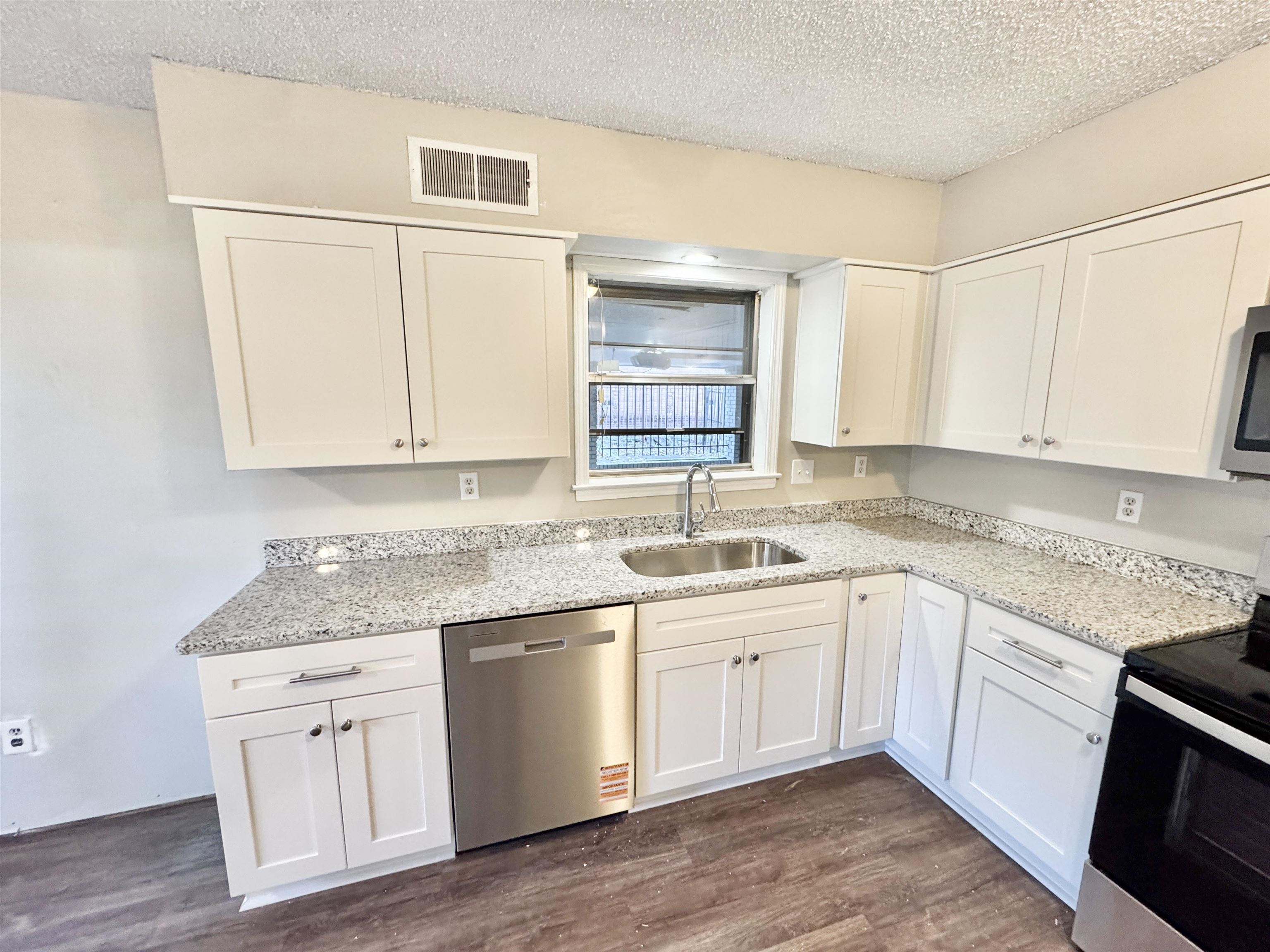 3836 Birchleaf Road Memphis, TN 38116 - Photo 15 of 40 Kitchen featuring appliances with stainless steel finishes, a textured ceiling, light stone counters, white cabinetry, and dark wood-style flooring