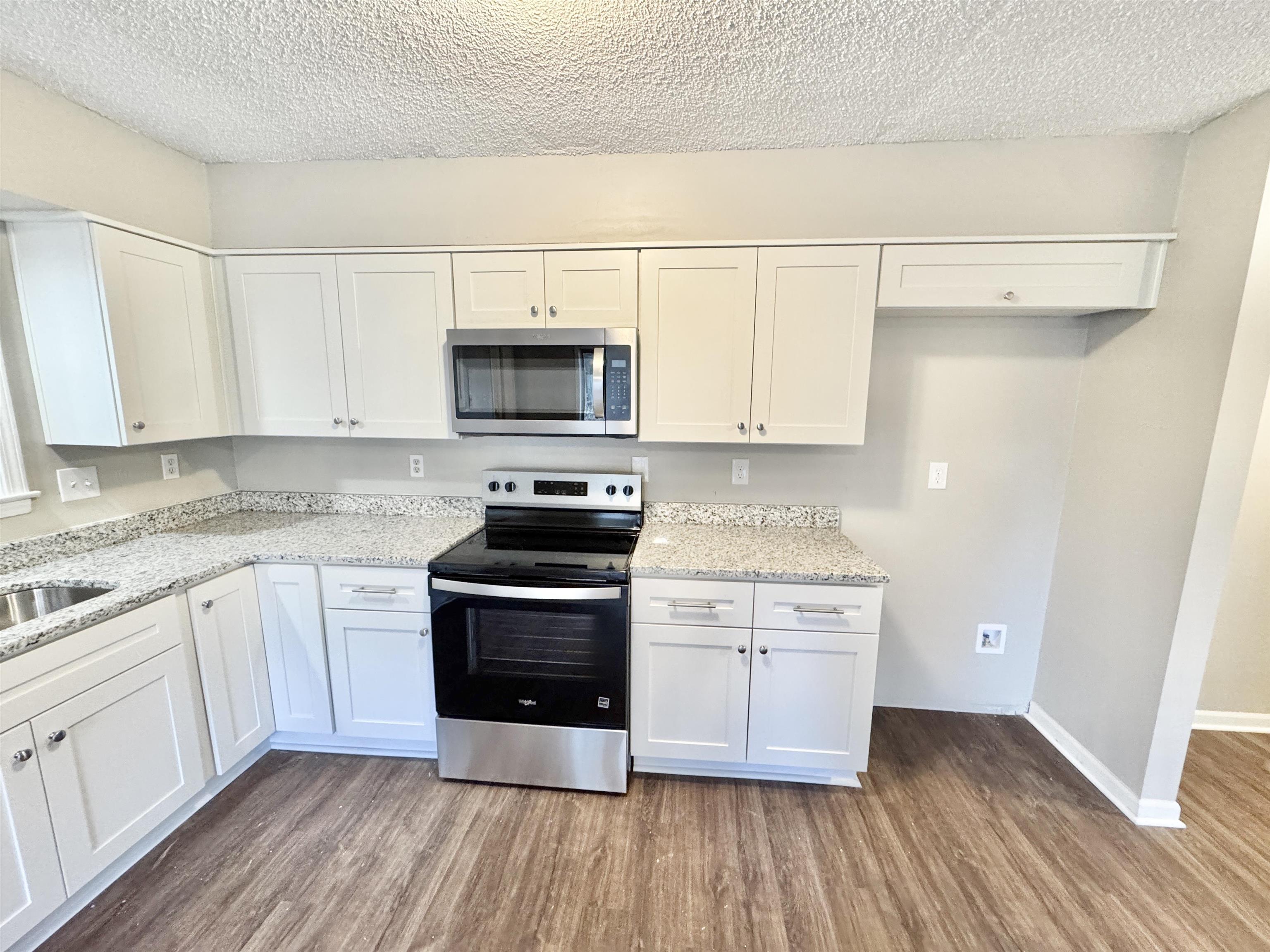 3836 Birchleaf Road Memphis, TN 38116 - Photo 16 of 40 Kitchen featuring appliances with stainless steel finishes, white cabinetry, dark wood-type flooring, and a textured ceiling