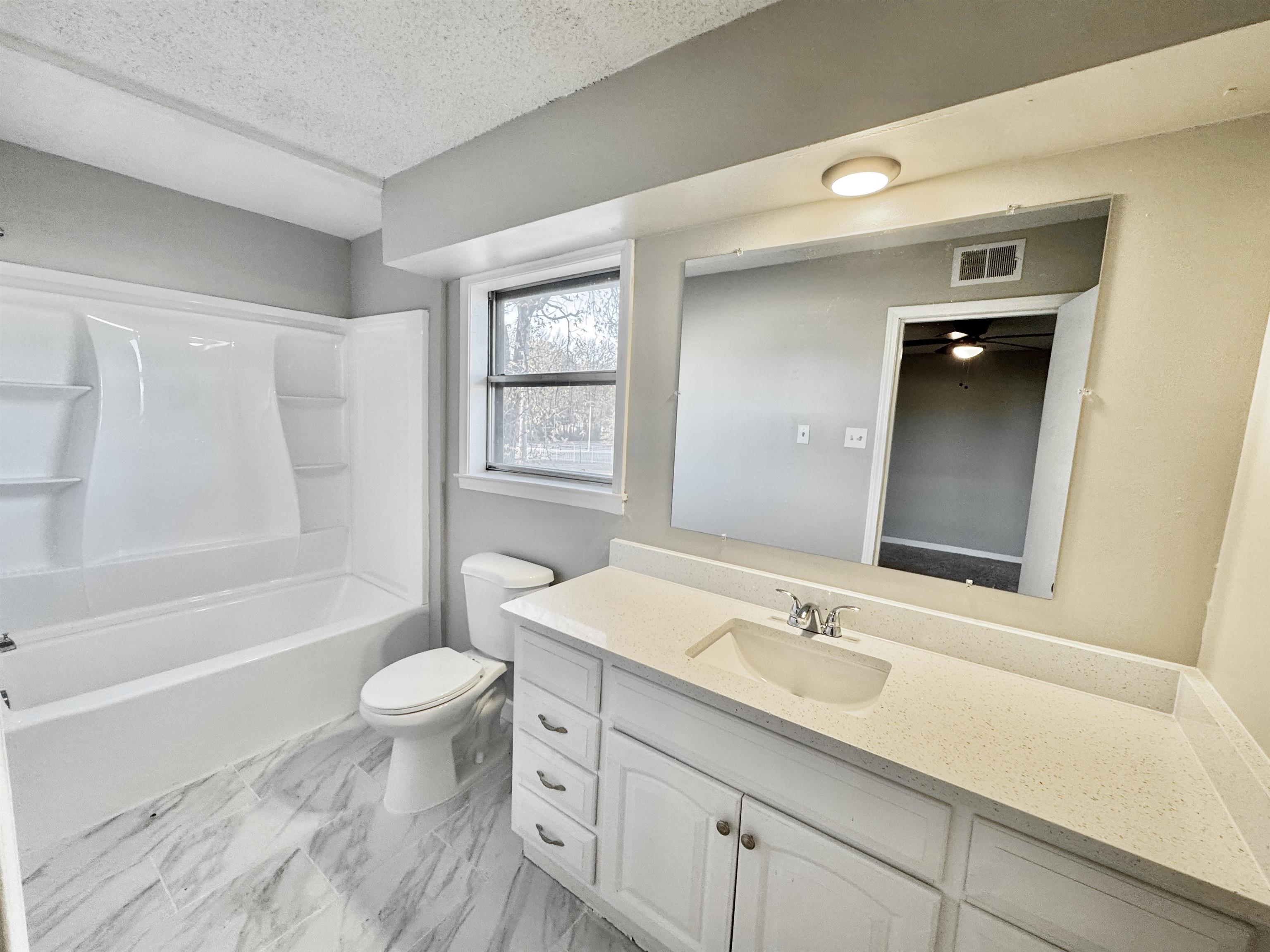 3836 Birchleaf Road Memphis, TN 38116 - Photo 29 of 40 Bathroom with vanity, a textured ceiling, shower / tub combination, and light marble finish floors