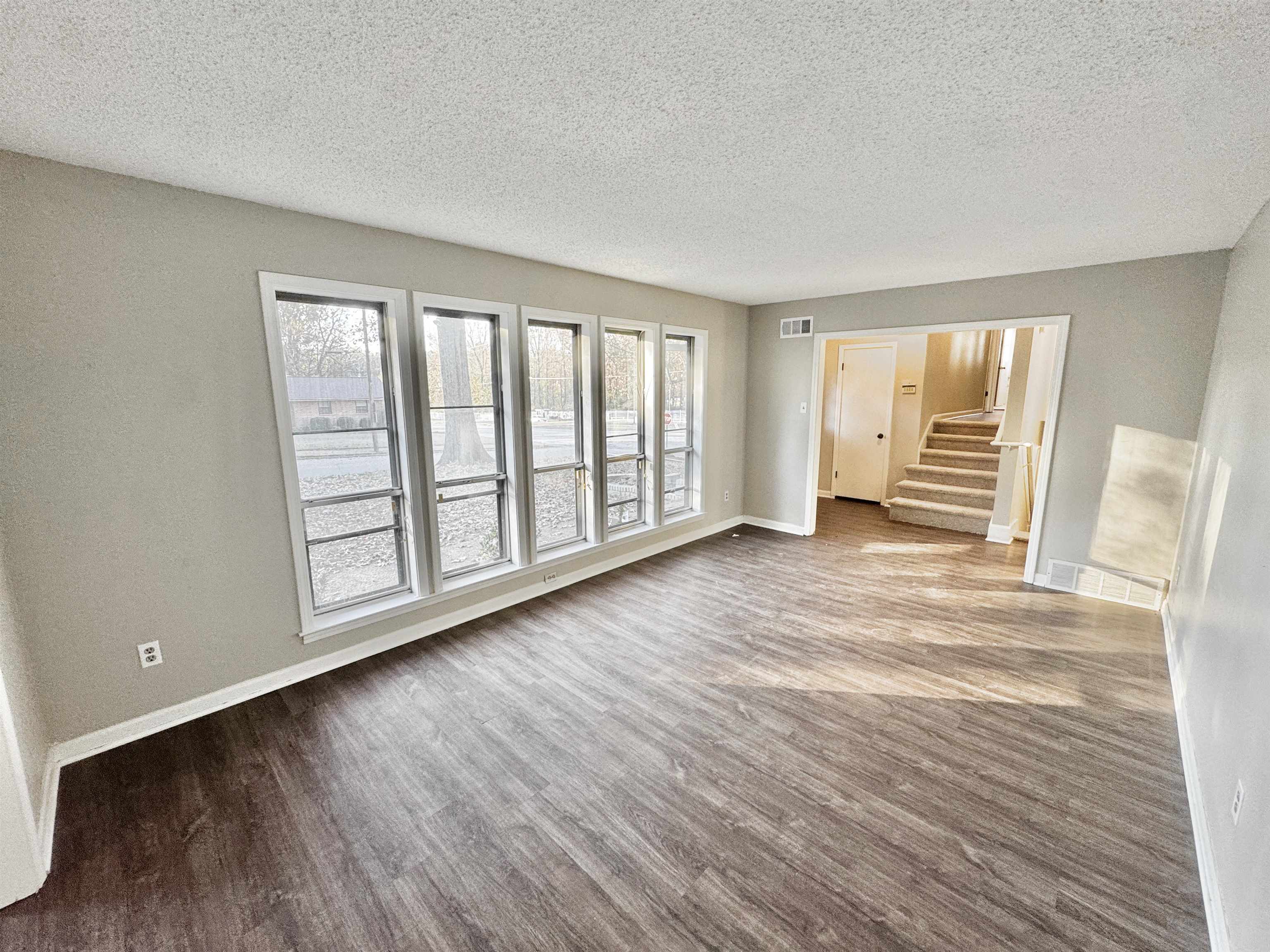 3836 Birchleaf Road Memphis, TN 38116 - Photo 9 of 40 Empty room featuring a textured ceiling, stairs, and dark wood-type flooring