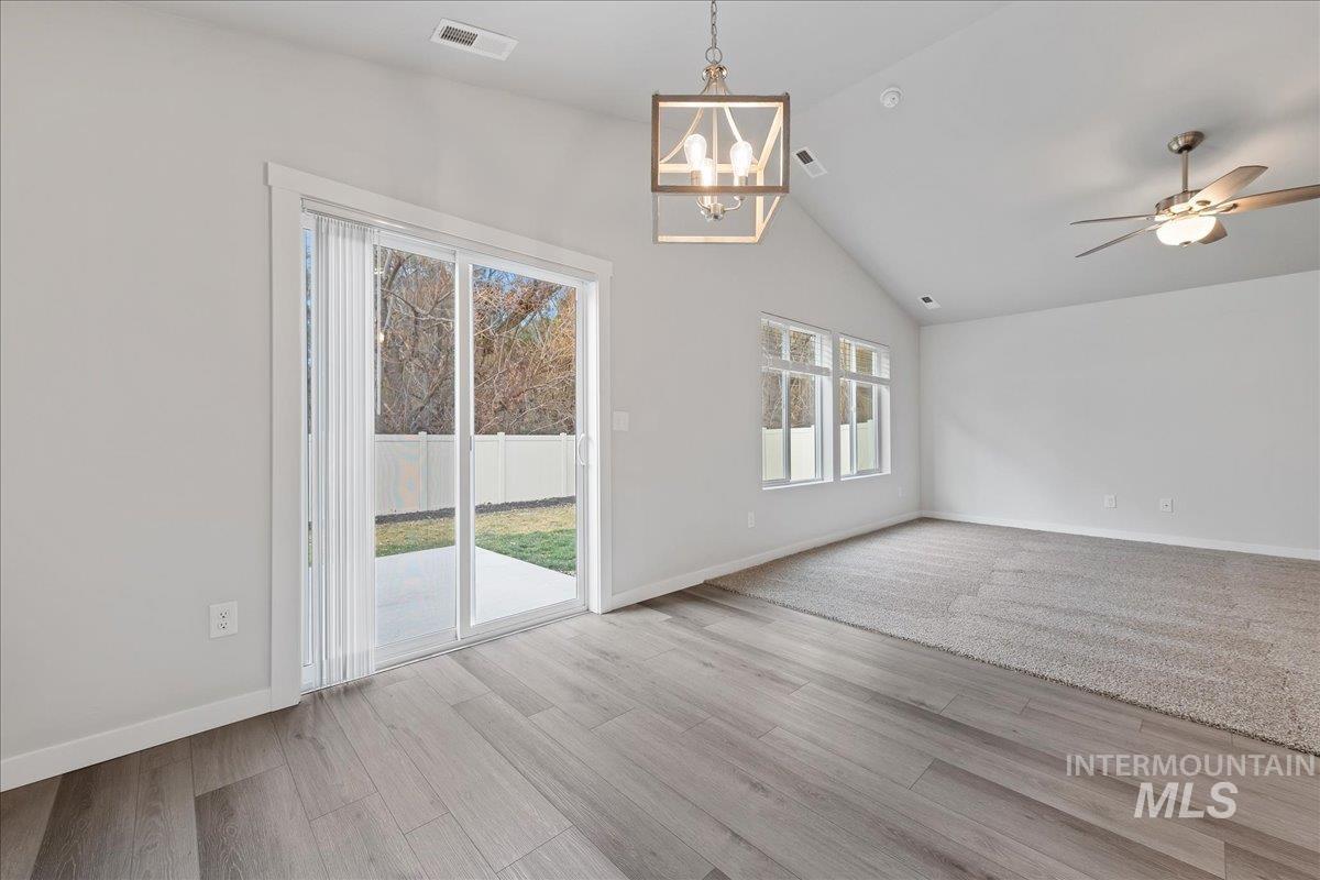 3079 S Green Boise, ID 83709 - Photo 11 of 35 Unfurnished dining area featuring ceiling fan, vaulted ceiling, a chandelier, and light wood finished floors