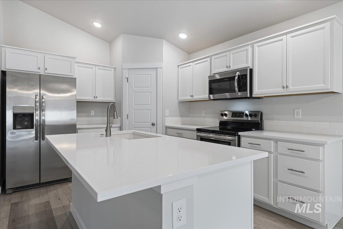 3079 S Green Boise, ID 83709 - Photo 13 of 35 Kitchen with stainless steel appliances, white cabinets, a center island with sink, lofted ceiling, and light stone counters