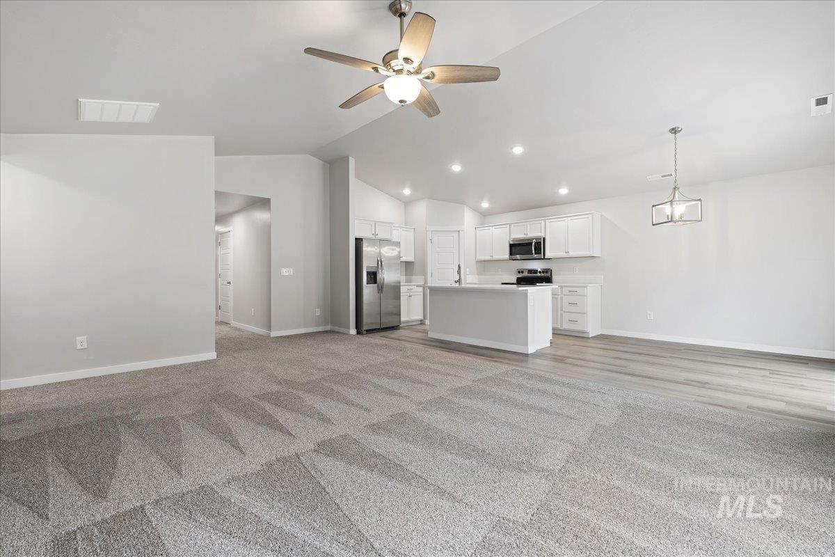 3079 S Green Boise, ID 83709 - Photo 8 of 35 Unfurnished living room featuring ceiling fan, lofted ceiling, light carpet, and recessed lighting