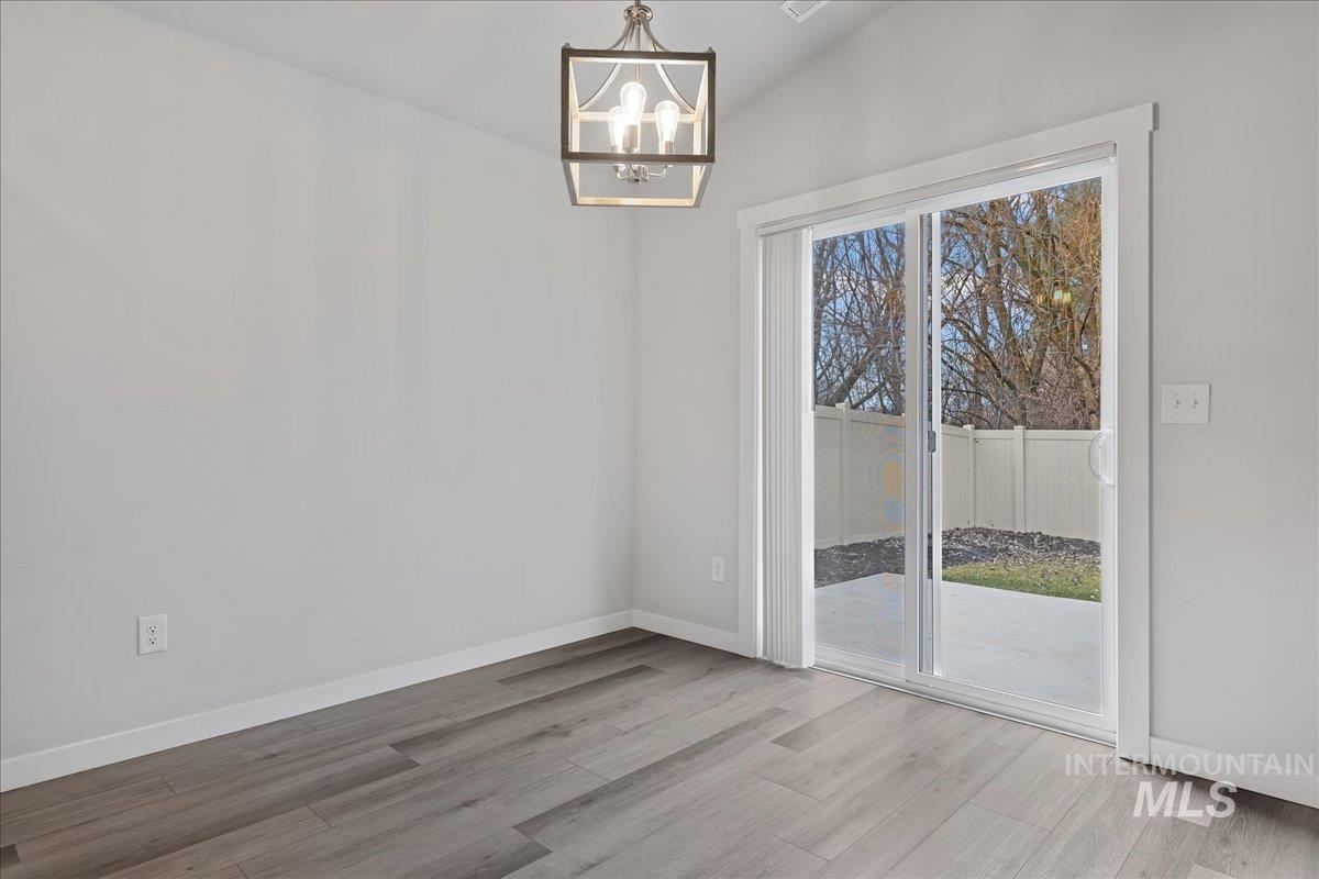 3079 S Green Boise, ID 83709 - Photo 10 of 35 Unfurnished dining area featuring a chandelier, lofted ceiling, and light wood finished floors